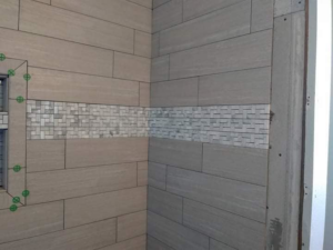 Close-up of a shower tile installation with decorative mosaic band by TaylorMade handyman services in Roswell, NM