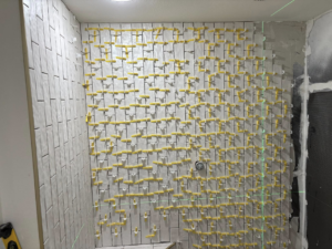 Shower tile installation with a laser level for precision by Considerate Repair in Walla Walla, WA.