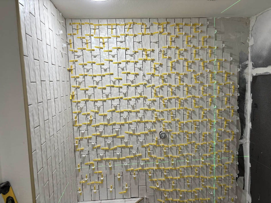 Shower tile installation with a laser level for precision by Considerate Repair in Walla Walla, WA.