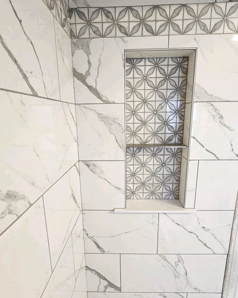 A close-up of a shower wall with a custom-built tile niche featuring decorative patterned tiles by Brian's Tiles in Duluth, MN.