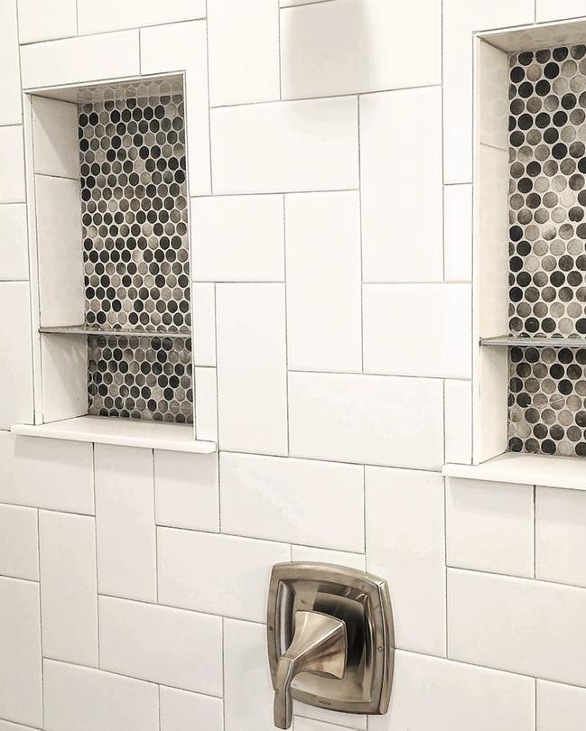 Close-up of shower wall with two tiled niches featuring dark mosaic accents, installed by Brian's Tiles in Duluth, MN.