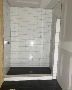 A shower stall with white subway tiles being installed during a bathroom renovation by Total Improvements LLC in San Antonio, TX