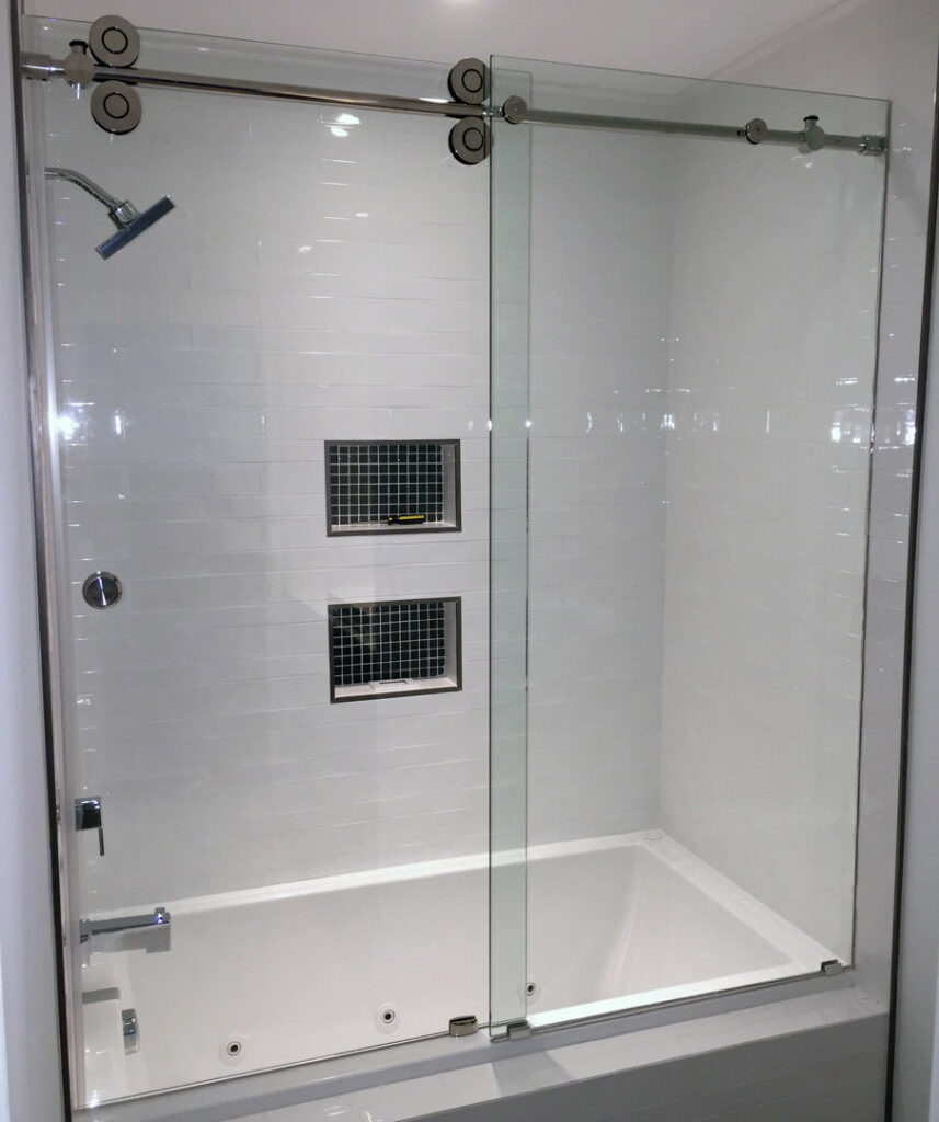 A renovated shower and tub combo with white subway tiles and built-in niches by Lehigh Shower Glass in Bethlehem, PA