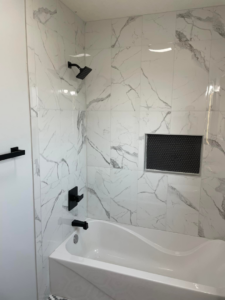 A newly tiled shower and tub area with modern black fixtures by Capital T's Home Specialty LLC in Topeka, KS.