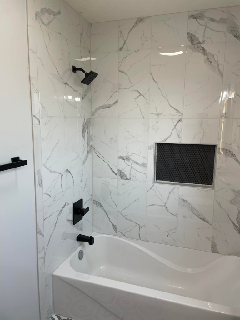 A newly tiled shower and tub area with modern black fixtures by Capital T's Home Specialty LLC in Topeka, KS.