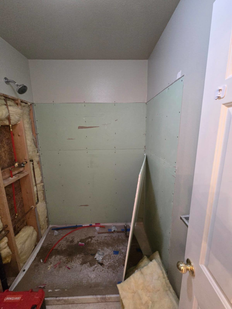 Installing green drywall backer board in a shower area during a bathroom renovation by Fullhouse Builders LLC in Gig Harbor, WA