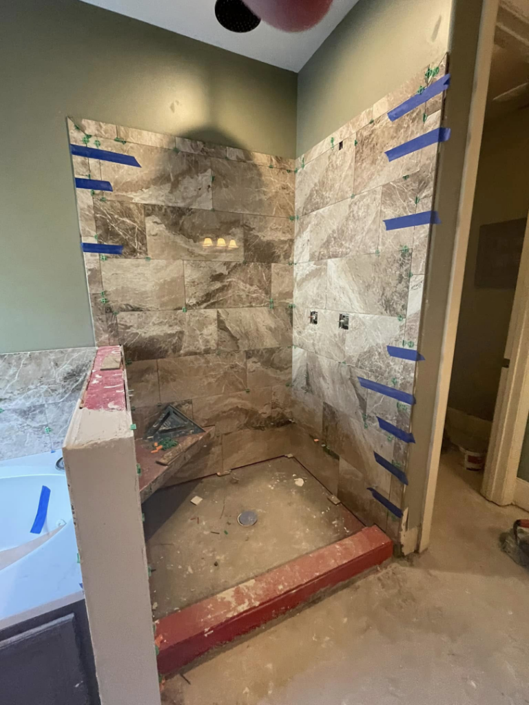 Shower wall tiling in progress, showing new tiles being installed with spacers, by RIBAM Residential contractor.llc in Auburn, AL.