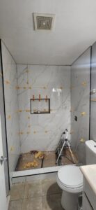 Shower walls being tiled with elegant marble-look tiles and spacers by Castillejo Handyman Services in San Diego, CA