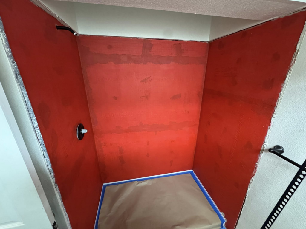 Shower walls prepped with a red waterproofing membrane before tiling by Peraza Handyman Services Llc in Bakersfield, CA.