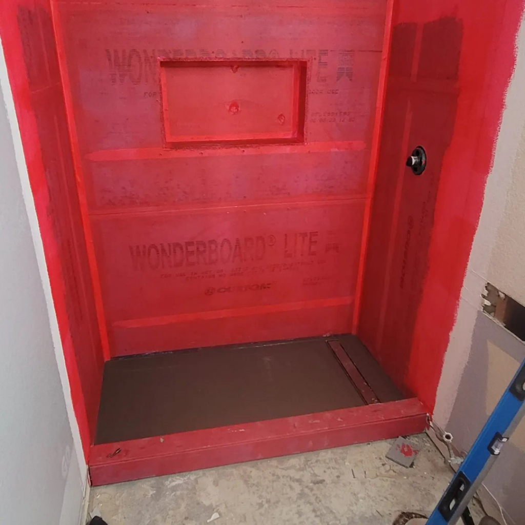 A shower stall with red waterproofing membrane and shower pan installed by Tier 1 Contracting Inc. in Apache Junction, AZ.