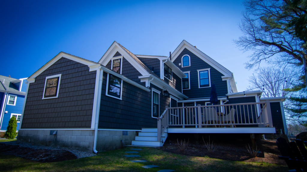The side exterior of a house with dark siding, white trim, and multiple windows, a project by Boston Exterior Remodeling in Boston, MA.