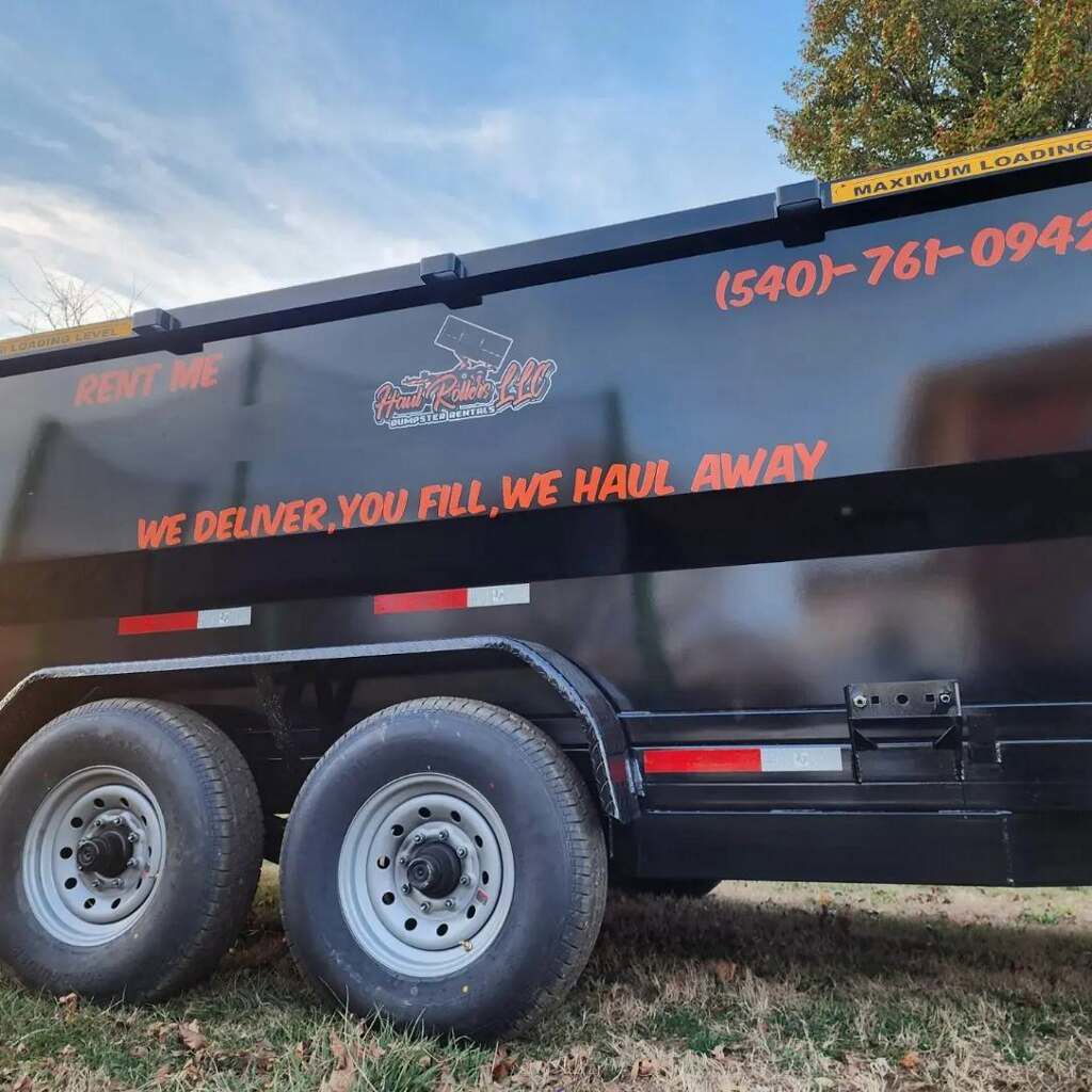 A close-up side view of a Haul Rollers LLC dump trailer with 'RENT ME' and service details for junk removal in Roanoke, VA.