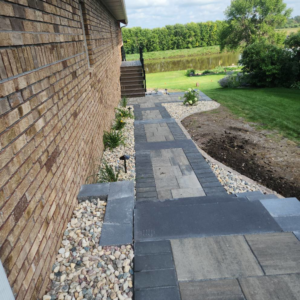 Side view of a finished paver walkway and steps next to a lake by Great Plains Remodeling and Handyman Services in Mitchell, SD.