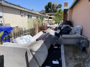 A side yard with a large pile of old furniture and household junk for removal by Eastlake Hauling and Junk Removal, LLC in Chula Vista, CA.