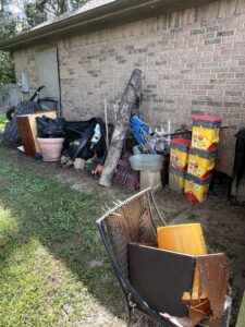 A large pile of mixed junk and debris in a side yard, ready for removal by Clear Your Junk - Pearland, Houston, TX.