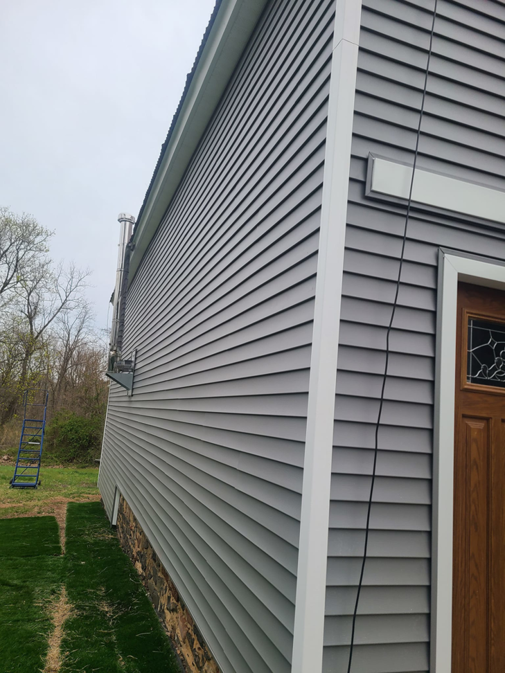 Corner of a building with new gray siding and door installed by Jos Construction LLC in Trenton, NJ.