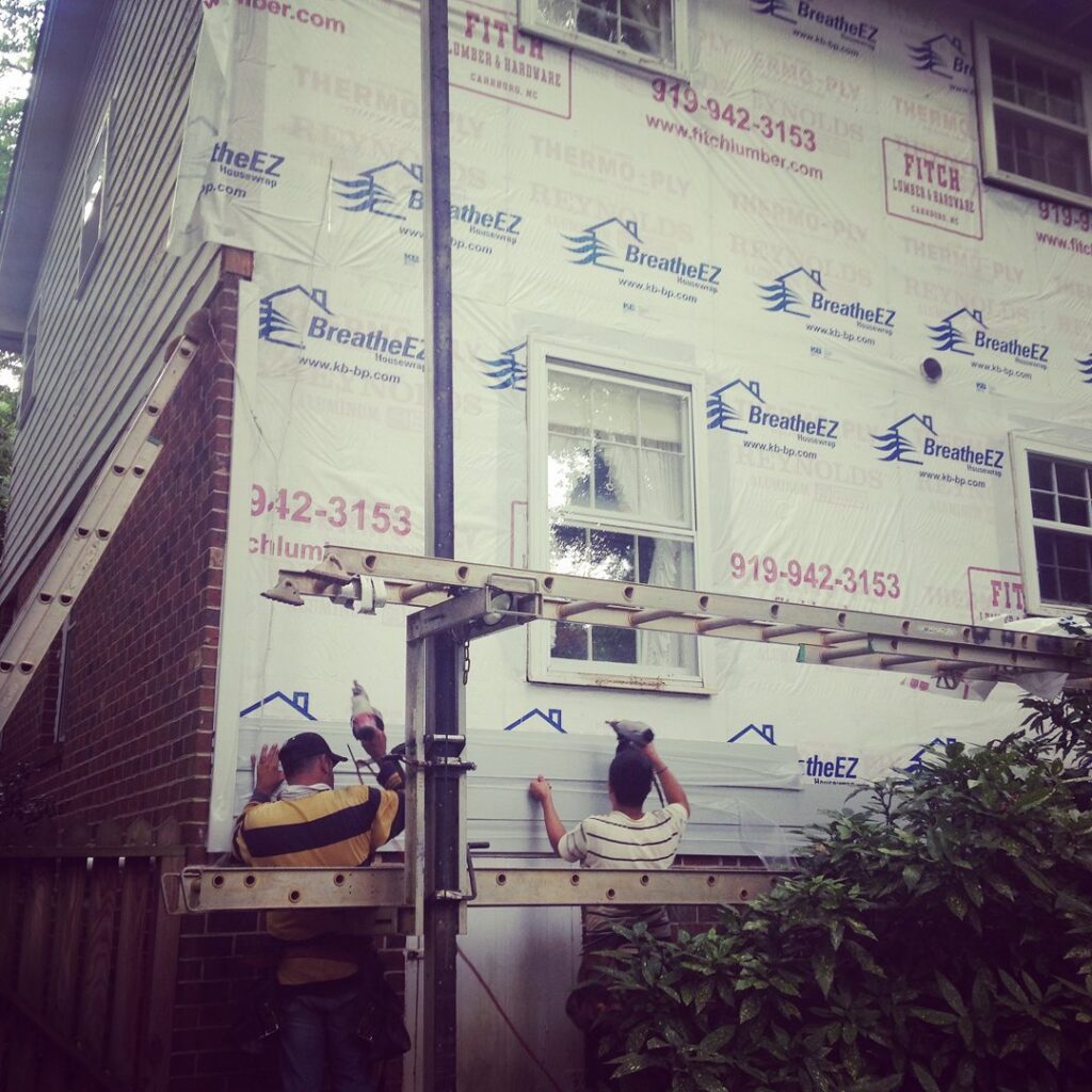 A crew installing new siding on a house, a handyman service by Consolidated Roofing Systems, Inc. in Cary, NC