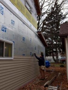 A handyman installing new siding on the exterior of a home, a service provided by GCB Home Improvement in Appleton, WI.