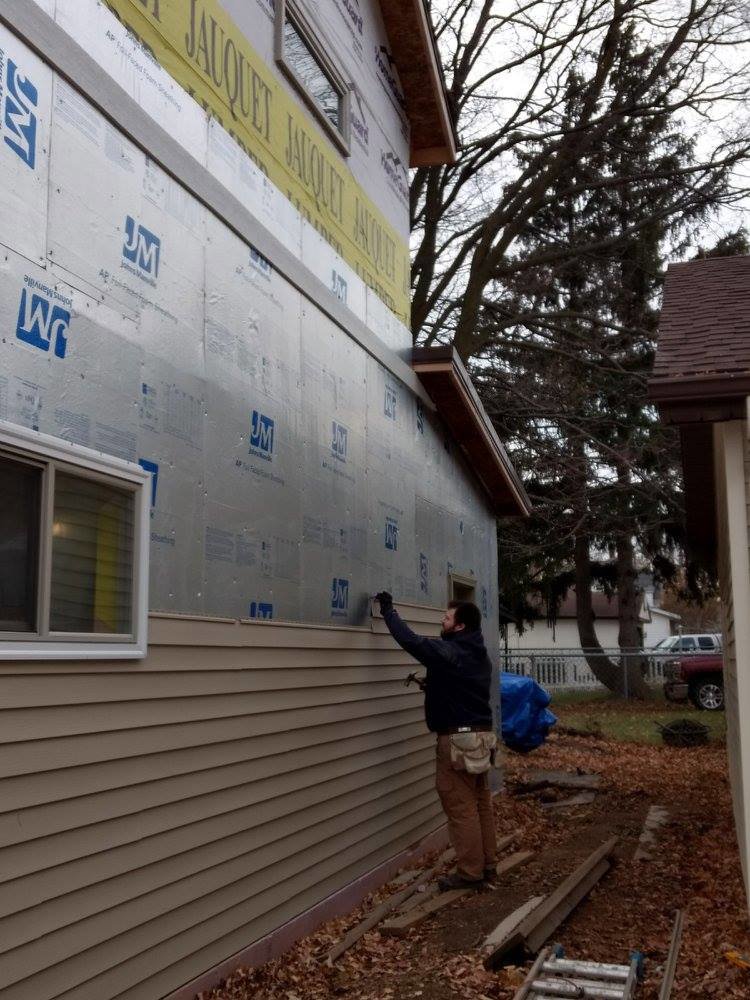 A handyman installing new siding on the exterior of a home, a service provided by GCB Home Improvement in Appleton, WI.