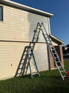 A close-up of a siding painting project in progress with two ladders by The First Choice Painting in San Antonio, TX