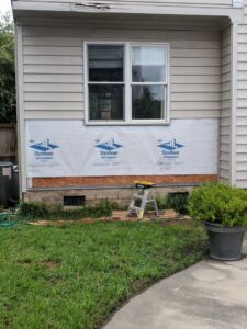 Exterior wall with insulation wrap and exposed framing during siding repair or installation by The Home Pros in Virginia Beach, VA