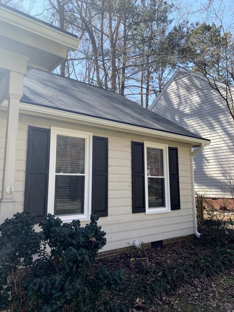 New siding, white windows with black shutters, and gutters installed by NC Siding and Windows in Raleigh, NC