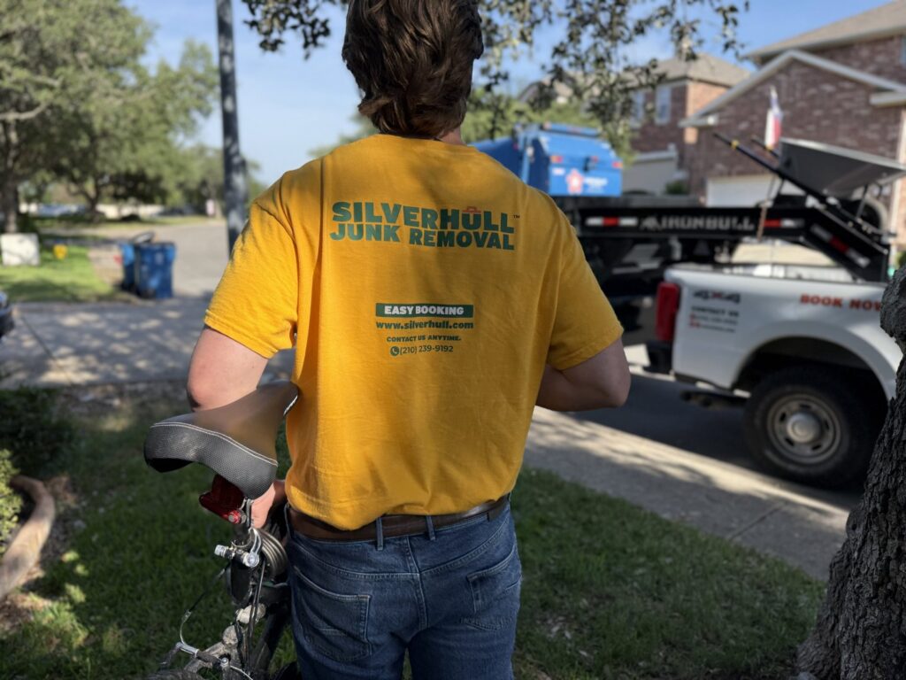 A Silverhull Junk Removal worker standing next to their truck and dump trailer in San Antonio, TX, ready for a job