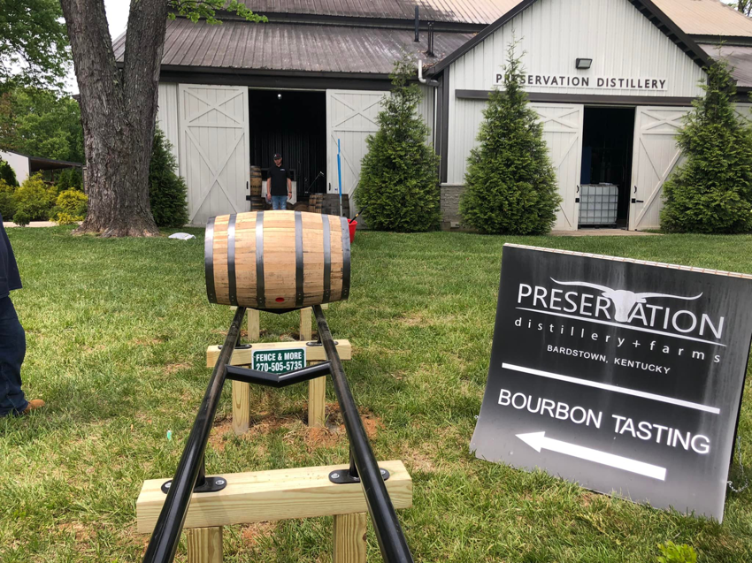 A single whiskey barrel on a custom display stand with a Fence & More sign in Elizabethtown, KY