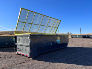 A single roll-off dumpster with its yellow safety net open, provided by First Light Services Llc in Casper, WY.