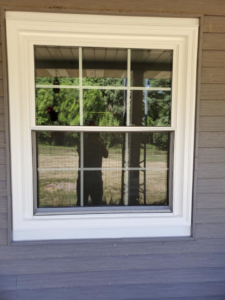 A single new window installation with white grid and screen on a house exterior by Hack's Construction & Window Co in Fishers, IN