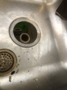 A kitchen sink drain with the stopper removed, indicating cleaning or repair services by Mancusi Home Maintenance in Boulder City, NV.
