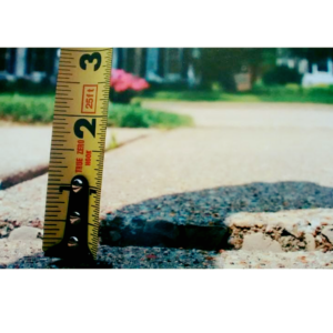 A tape measure showing a significant gap in a sinking concrete slab, indicating a need for repair by American Mud Jack INC in Arvada, CO.