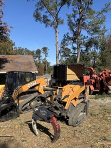 A skid steer, wood chipper, and dump truck full of chips for tree service cleanup by 706 Tree and Stump in Augusta, GA.