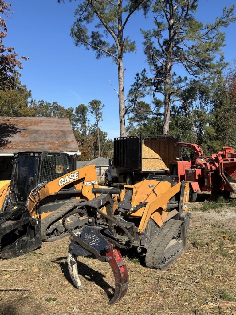 A skid steer, wood chipper, and dump truck full of chips for tree service cleanup by 706 Tree and Stump in Augusta, GA.