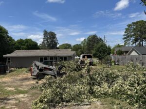 A skid steer clearing branches and debris in a yard after tree work by De Paz Tree Service in Katy, TX