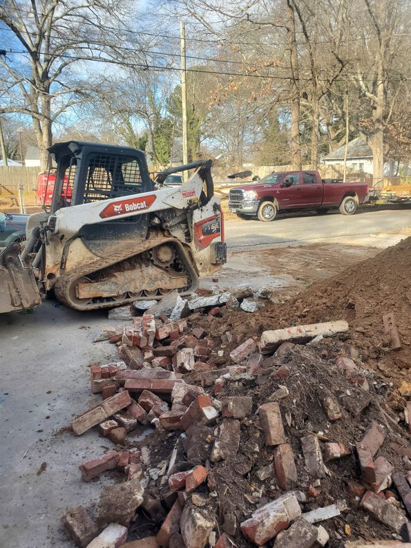 A Bobcat skid-steer loader next to a pile of brick and dirt debris, handled by Standard Dumpster LLC in Rock Hill, SC.