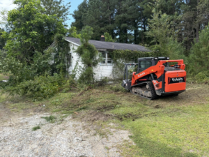 A skid steer loader clearing an overgrown property for BRR services in Fayetteville, NC