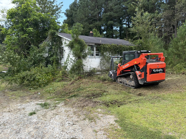 A skid steer loader clearing an overgrown property for BRR services in Fayetteville, NC