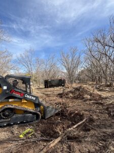 A skid steer clearing trees and brush from a property for Sandia Valley Services LLC in Rio Rancho, NM.