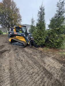 A John Deere skid steer with a grapple attachment clearing trees and brush for DLL Landscaping & Tree Service in Columbus, OH.