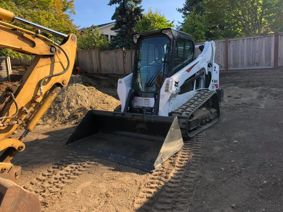 A skid steer and excavator on a job site, used by M.C.Dirtworks for handyman services in Caldwell, ID.