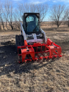 A skid steer with a grapple attachment removing brush and debris for Falcon Enterprises LLC in Pierre, SD