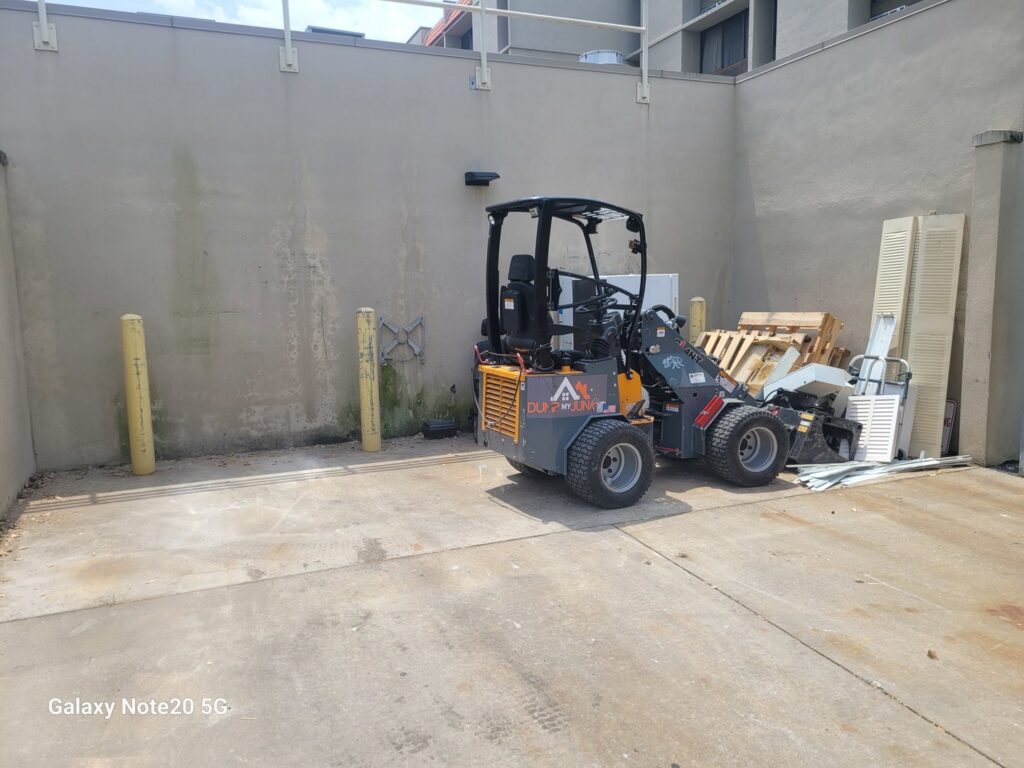 A skid steer loader next to a pile of debris, ready for removal by Dump My Junk LLC Demolition & Dumpster Rental in Tampa, FL.