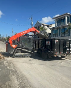 A skid steer loading construction debris into a dumpster trailer for Dumpster Rental Florida in West Park, FL.