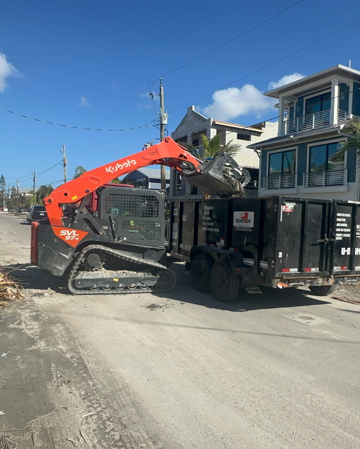 A skid steer loading construction debris into a dumpster trailer for Dumpster Rental Florida in West Park, FL.