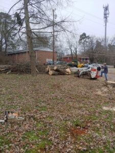 A mini skid steer moving logs and tree debris after a tree service job by Ole' Smokey's Tree Service in Knoxville, TN.