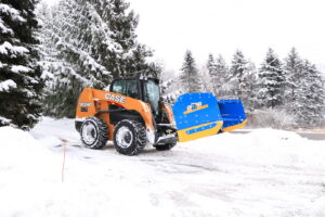 A skid steer with a snow plow attachment clearing snow from a driveway for Schifsky Companies in Lake Elmo, MN.
