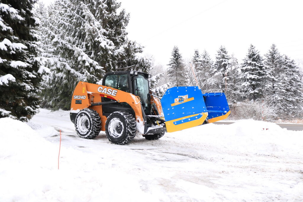 A skid steer with a snow plow attachment clearing snow from a driveway for Schifsky Companies in Lake Elmo, MN.