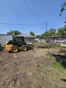 A skid steer with an attachment used for clearing tree branches and debris by Alpha Outdoor Services LLC in Kearney, NE.