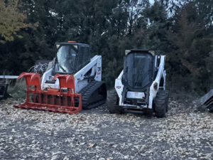 Two Bobcat skid steers, one with a grapple attachment, ready for tree service work by Falcon Enterprises LLC in Pierre, SD